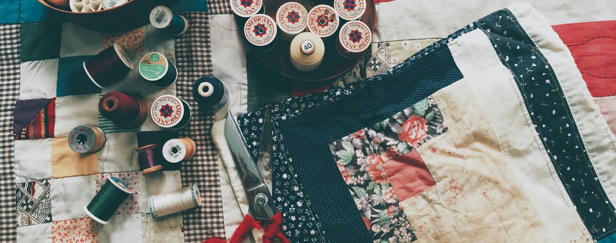 A picture of a quilt, along with different colored spools of thread.